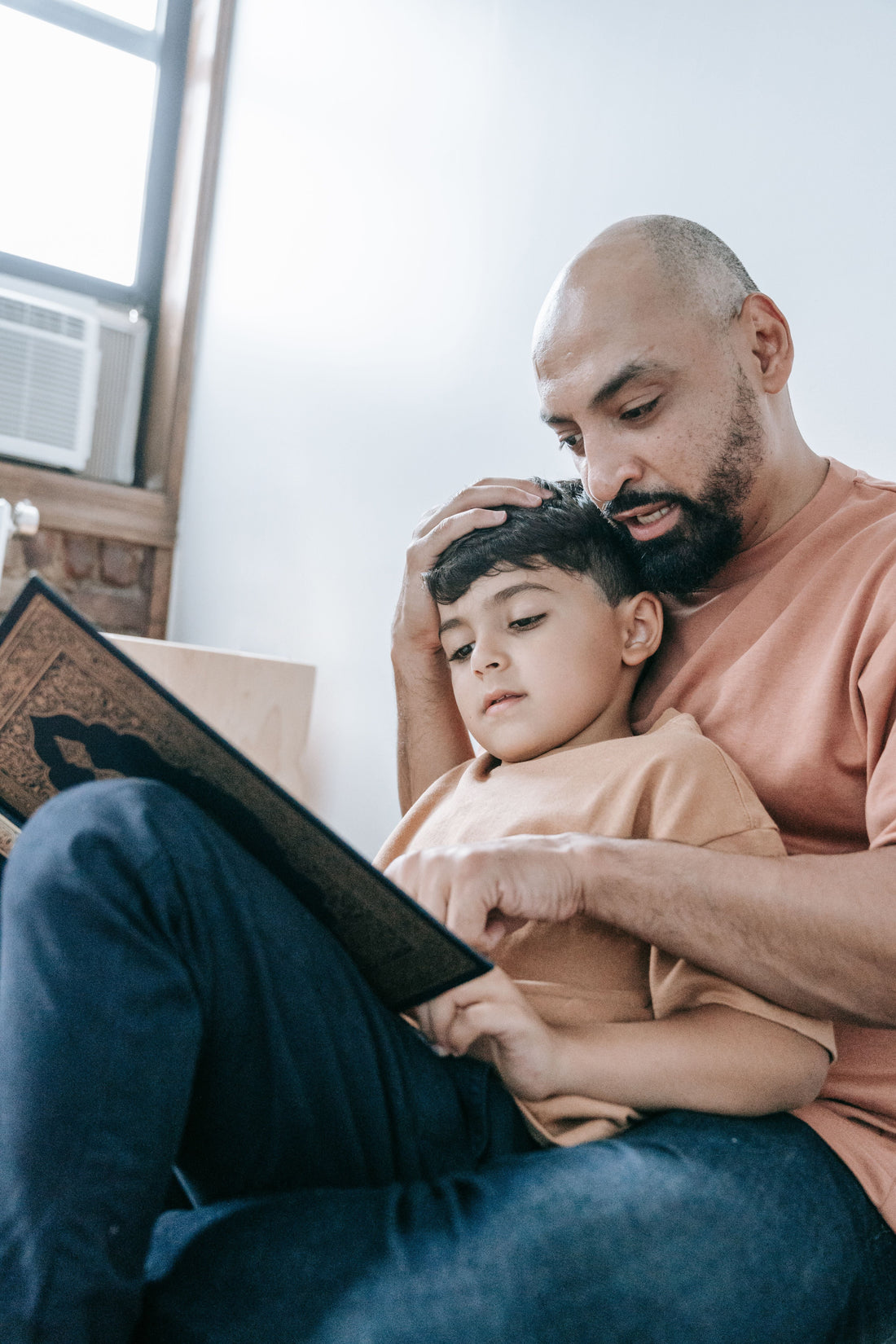 An adult and child reading a book together.