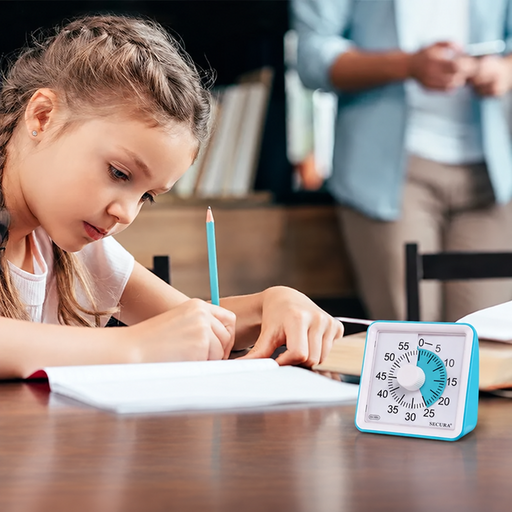 A student writing at a desk with the blue Secura visual timer beside her notebook.