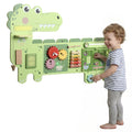 A child standing beside the green Qaba dinosaur wall busy board and exploring its sliding maze.